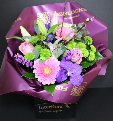 Hand tied pink roses, pink Gerbera, stargazer lily, green santini chrysanthemum, purple Lissianthus, Vanda Orchid & pussy willow bound with selective foliage.